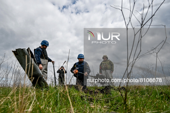 HRYHORIVKA, UKRAINE - APRIL 20, 2022 - An expert of a State Emergency Service bomb squad digs around the dangerous remains of an Uragan rock...