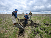 HRYHORIVKA, UKRAINE - APRIL 20, 2022 - An expert of a State Emergency Service bomb squad digs around the dangerous remains of an Uragan rock...