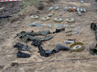 KYIV REGION, UKRAINE - APRIL 21, 2022 - Boots and the pieces of Russian uniforms as well as explosives are arranged on the ground during a m...