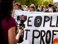 A woman takes video of Fridays for Future's banner after demonstrators joined 350.org’s Fossil Free Federal Reserve Earth Day protest.  Demo...