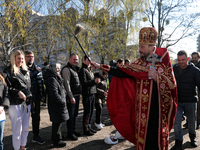 BUCHA, UKRAINE - APRIL 24, 2022 - A priest blesses people and their baskets with holy water outside the Church of Saint Andrew the First-Cal...