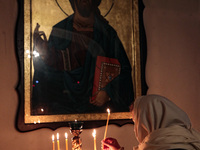 BUCHA, UKRAINE - APRIL 24, 2022 - A woman leaves a burning candle on a stand during an Easter liturgy in the Church of Saint Andrew the Firs...