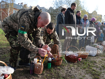 BUCHA, UKRAINE - APRIL 24, 2022 - Servicemen light candles inserted in paskas before a consecration ceremony outside the Church of Saint And...