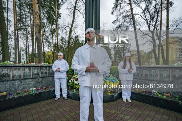 People dressed like workers of the Chernobyl Nuclear Plant hold candles during the celebrations of the 36th anniversary of the accident of t...