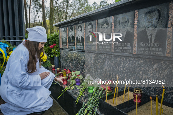A woman dressed like a worker of the nuclear plant, put a candle in the memorial of the dead workers in the catastrophe of Chernobyl during...