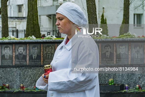 A woman dressed like a worker of the Chernobyl nuclear plant, holds a candle near the memorial of the dead workers in the catastrophe of Che...
