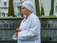 A woman dressed like a worker of the Chernobyl nuclear plant, holds a candle near the memorial of the dead workers in the catastrophe of Che...
