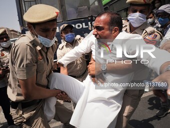 Delhi Police personnel detain an activist of the Indian Youth Congress (IYC) party as he tries to cross barricades during a protest against...