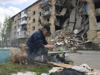 Local man warms water on the fire close to a residential building destroyed during Russia's invasion of Ukraine in Hostomel, Ukraine April 2...