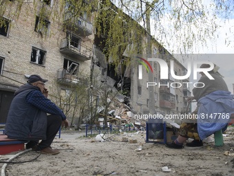 Local residences sit close to a residential building destroyed during Russia's invasion of Ukraine in Hostomel, Ukraine April 29, 2022. (