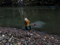 A woman is seen throws garbage into the Cisadane River in Bogor, West Java, Indonesia on May 2, 2022. The residents of riverbank settlements...