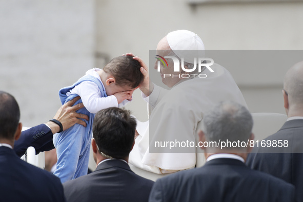 Pope Francis kisses a child as he arrives on the popemobile to attend his weekly open-air general audience in St. Peter's Square at The Vati...