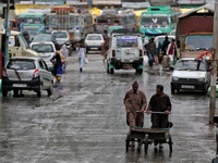 Kashmiri men push a hand cart during rainfall in Baramulla, Jammu and Kashmir, India on 06 May 2022 (
