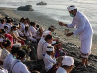Balinese Hindu devotees receive holy water as they pray during the Melasti, a purification ceremony ahead of Nyepi at a beach in Bali, Indon...