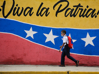 A boy walks in front of a mural that in Spanish says: Long live the homeland, by the west side of the city in Caracas, Venezuela on May 9, 2...