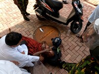 An anti-government Sri Lankan monk who got injured after being attacked by government supporters lies down as a catholic priest helps amid t...
