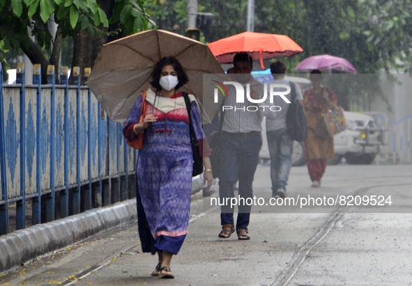 People carry umbrella during rainfall in Kolkata, India, 10 May, 2022. 