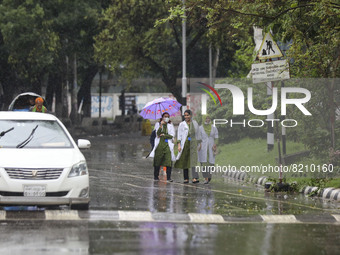 People make their way during rainfall  into a deep depression, in Dhaka, Bangladesh on May 10, 2022.. (