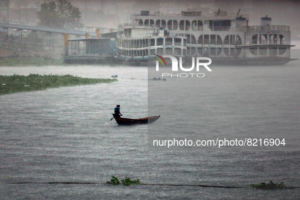 A boatman crosses the river Buriganga by boat during rain in Dhaka, Bangladesh on May 12, 2022. 