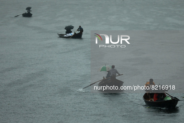 Passengers cross the river Buriganga by boat as they hold during rain in Dhaka, Bangladesh on May 12, 2022. 