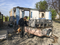 A local farmer Serhiy carries hens near his house destroyed during the Russian occupation of Zahaltsi village near Kyiv, Ukraine, ​May 13, 2...
