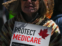 A protester holds a placard with words 'Protect Medicare. Don't Privatize It!'.
Health-care workers, activists and their supporters proteste...