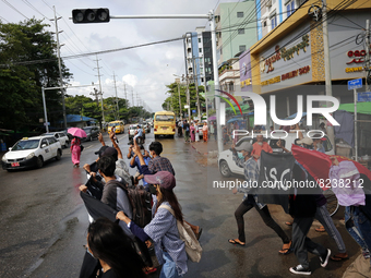 A group of young demonstrators shout slogans and make the defiant three-finger salute as they march during an anti-coup protest in Yangon, M...