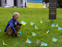 A man is setting up an makeshift memorial with Ukrainian flags for Ukrainian civilians and foreign citizens killed by Russian servicemen dur...