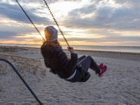 A woman swinging on a swing at the beach during a sunset is seen in Jurmala , Latvia on 5 May 2022 Jurmala is a resort town about 25 km west...