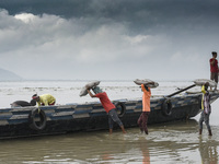 Labourer loading cement bags in a boat in the Brahmaputra river, in a cloudy day, in Guwahati, Assam, India on 17 May 2022.  (