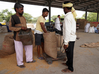 Labourers fill a sack with grains of wheat at a wholesale grain market near Sonipat, on the outskirts of New Delhi, India on May 17, 2022. I...
