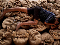 A labourer sleeps over stacked sacks of wheat at a wholesale grain market near Sonipat, on the outskirts of New Delhi, India on May 17, 2022...