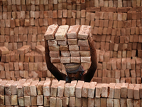 A Laborer unloads bricks from a cargo ship at the Kamrangirchar area in Dhaka, Bangladesh on May 18, 2022. (