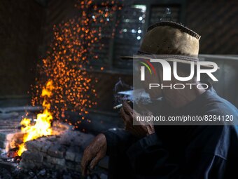 Supardi Seswowarsito, 71, smokes as traditional Javanese Keris daggers are made at a workshop on May 20, 2022, in Sleman District, Yogyakart...