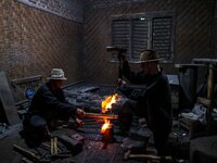 Ki Empu Sungkowo Harumbrodjo, 68, with his assistant, Supardi Seswowarsito, 71, hammers steel as he makes a traditional Javanese Keris dagge...