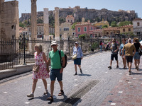Tourists are enjoy their time near Monastiraki square with Acropolis hill in the background in the center of Athens, Greece on May 25, 2022....
