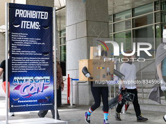 A person carries an imitation chainsaw past a sign listing prohibited items at the entrance to the 2022 Awesome Con comic convention at the...