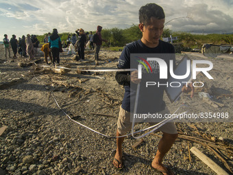 An environmental activist measures the limit of taking plastic waste samples on Palu Bay Beach, Central Sulawesi Province, Indonesia on June...