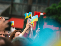 people waves Ukrain flags as Ukrainian singer Ruslana sings during the Benefit concert held in support of the Ukrain people who affected by...