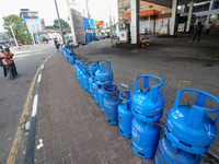 Sri Lankans walk across a street filled with chained empty domestic gas cylinders kept in front of a deserted gas station that is closed due...