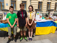 Kyiv scouts, Sergey, Volodymyr and Daryna sell collect donations for Ukrainian Army during a Holy Mass on Holy Trinity Holiday, also called...