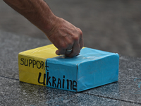 A person puts money into the box with the words 'Support Ukraine'.Members of the local Ukrainian diaspora, war refugees, peace activists, v...