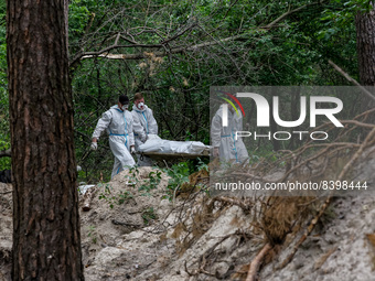 An excavation team carries a body of Ukrainian civilian murdered by Russian army in a forest near Bucha, Ukraine - June 13, 2022. The bodies...