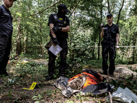 Policemen work in a forest near Bucha, Ukraine during excavation of bodies of Ukrainian civilians murdered by Russian army  - June 13, 2022....