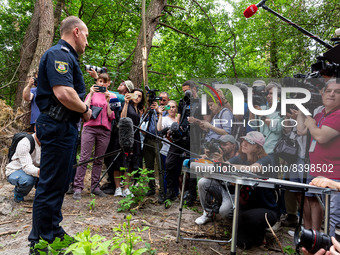 A policeman speak to media during a mass grave excavation procedure in a forest near Bucha, Ukraine on June 13, 2022. The bodies were discov...