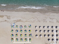 Aerial images from a drone of the coast of Rethymno town with the long beach and the beach bars in Creta island. People are seen enjoying th...