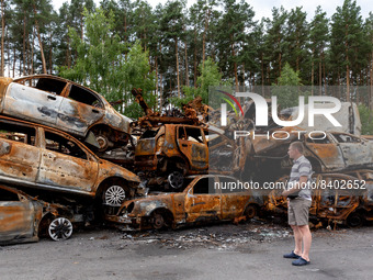A man watches burned cars on a parking destroyed by bombardment on June 14, 2022 in Irpin, Ukraine.  The cars were collected from the street...