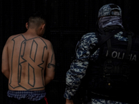 A police officer escorts a Barrio-18 gang member into a detention center on April 25, 2022 in San Salvador, El Salvador.  (