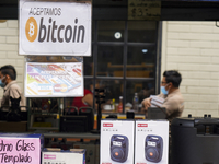 People walk as a sign is displayed announcing the acceptance of Bitcoin as a payment method on June 15, 2022 in San Salvador, El Salvador. E...