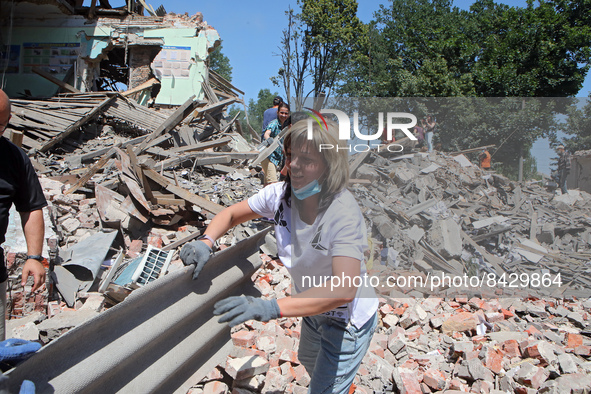 LIUBOTYN, UKRAINE - JUNE 20, 2022 - A woman passes a piece of fiber cement at the Liubotyn Railway Transport Lyceum which hosted a humanitar...